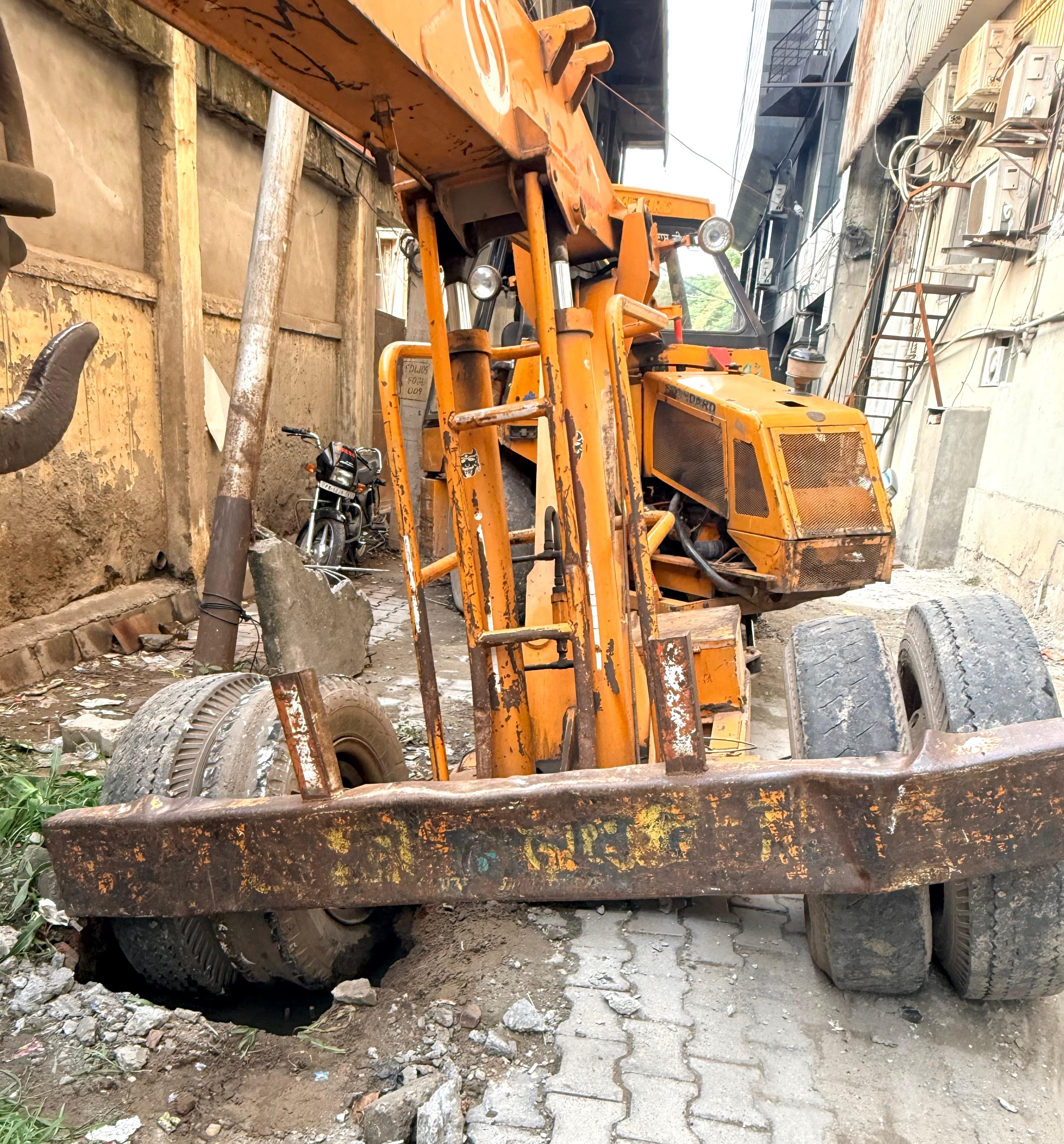 सीवरेज का ढक्कन टूटने से बीच में धंसी जेसीबी, बाल बाल हुआ बचाव